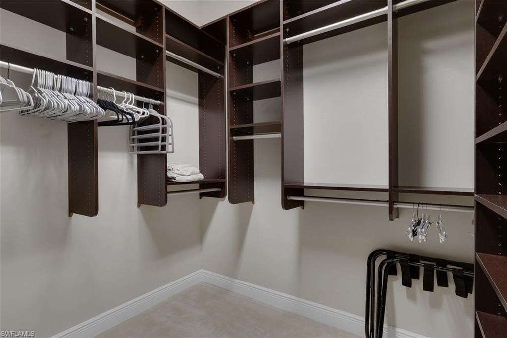 Walk-in closet with dark built-in shelving, hanging rods, and rows of hangers.