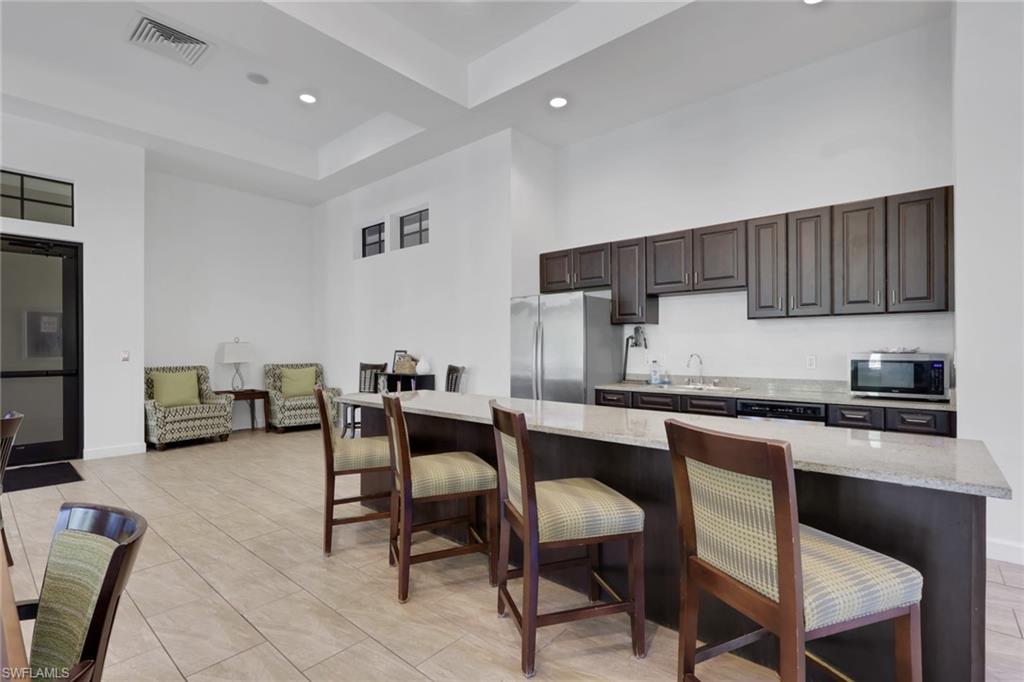 Kitchen with a long breakfast bar, dark wood cabinetry, and stainless steel appliances.