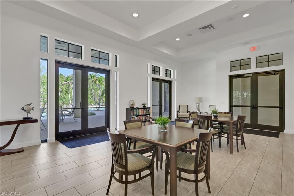 Furnished dining room with multiple tables and chairs beside glass doors opening to a patio.