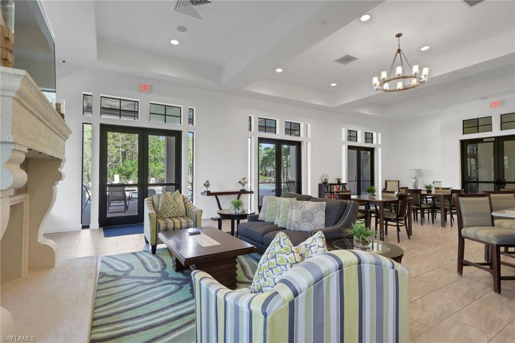 Furnished living room with stone fireplace, striped armchairs, large glass doors, and an adjoining dining area.
