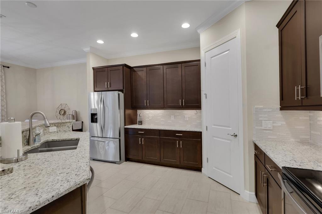 Kitchen with dark brown cabinets, granite counters, and a stainless steel refrigerator.
