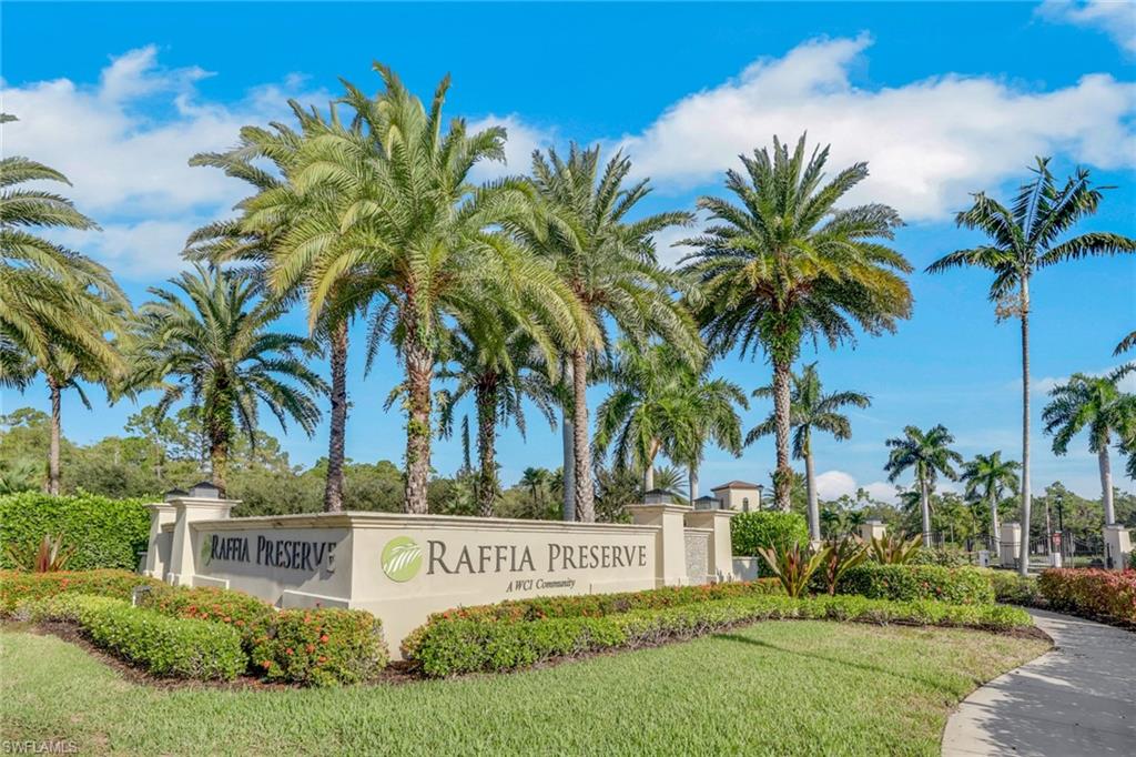 Raffia Preserve entrance sign surrounded by flowering landscaping and tall palm trees.