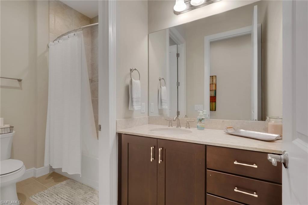 Bathroom with a dark wood vanity, large mirror, and white-curtained shower.