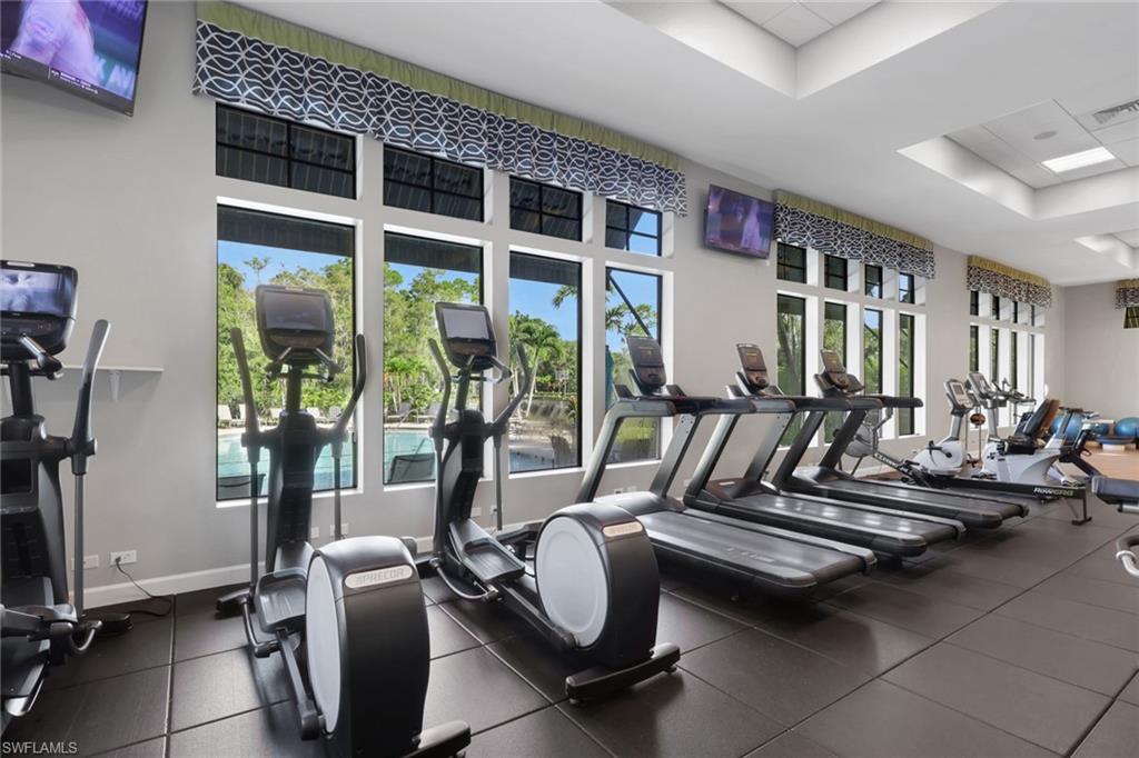 Fitness center with rows of cardio machines beside windows overlooking a pool.