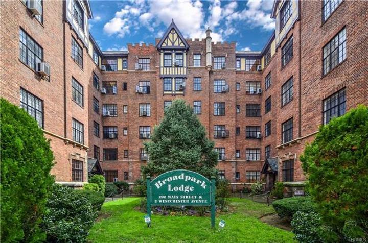 Red-brick apartment building around a landscaped courtyard, with a Broad Park Lodge sign.