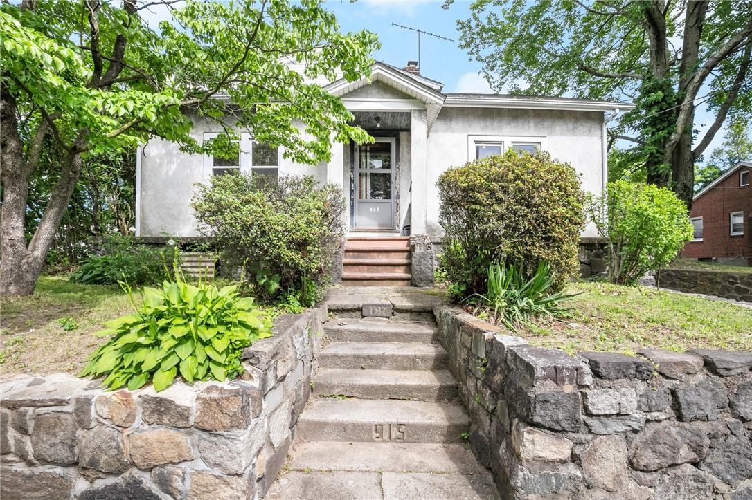 White house with a centered entry, stone retaining walls, and steps marked 915.