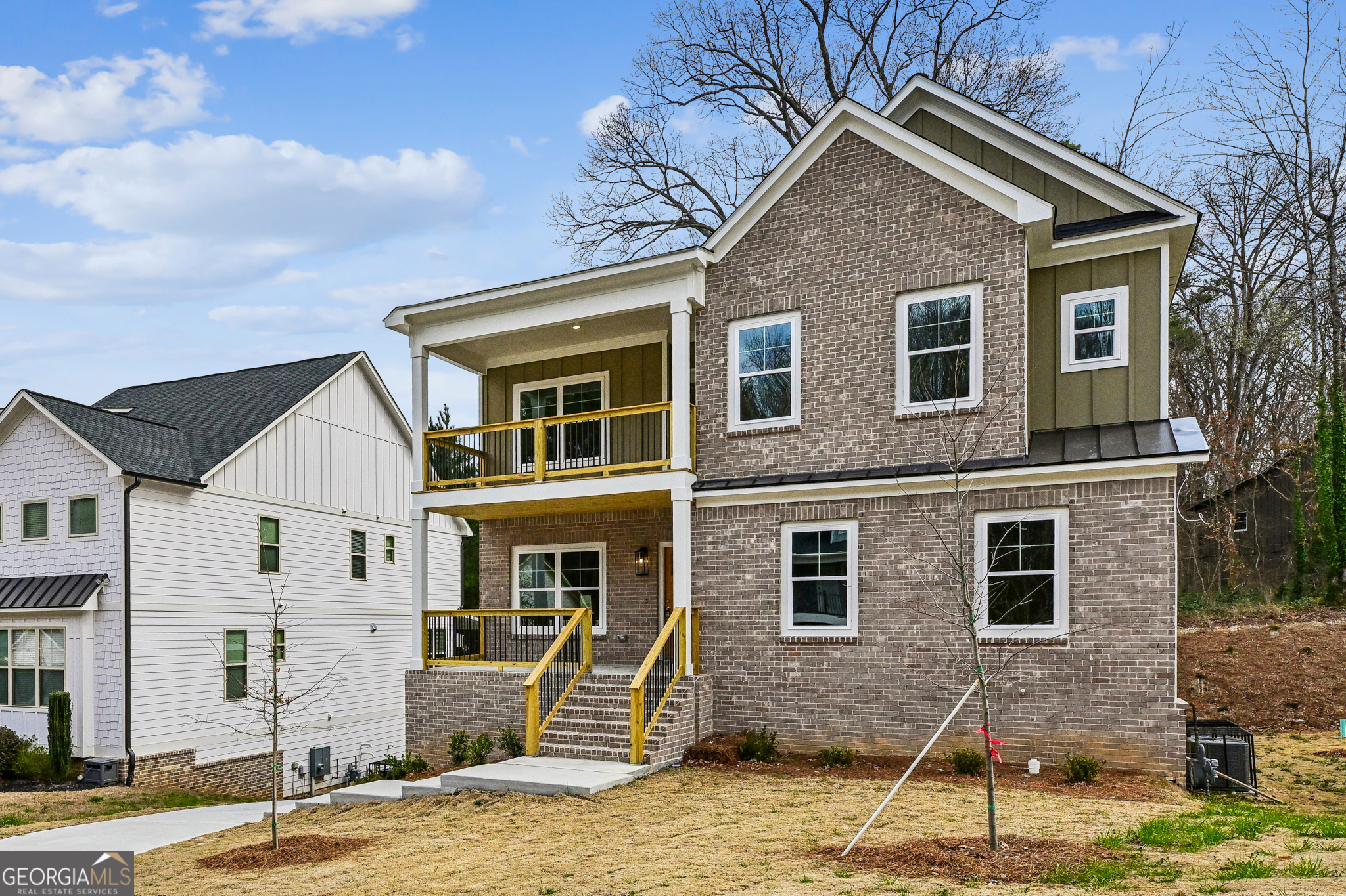 Two-story brick house with white trim, yellow-railed porches, and front steps.