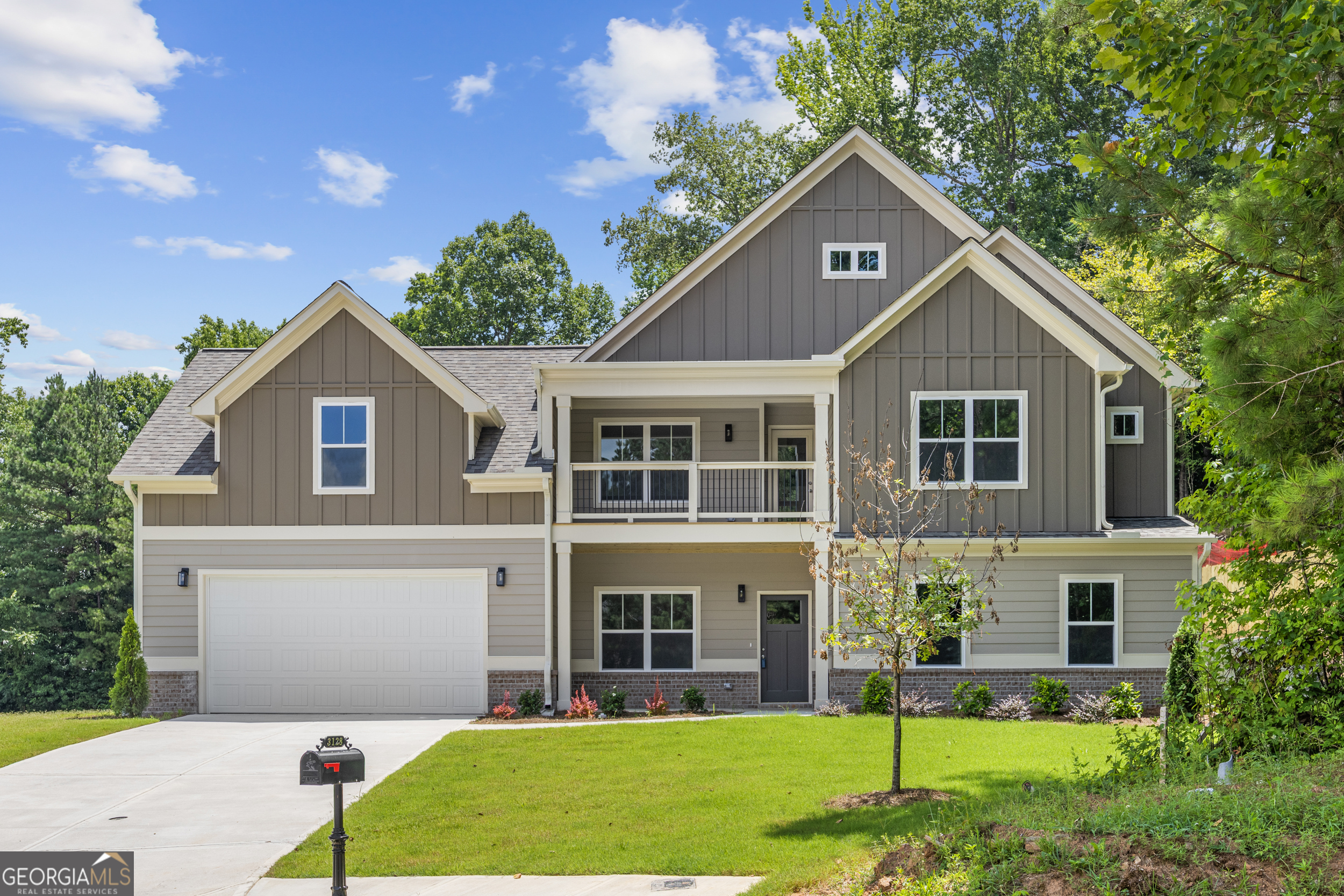 Two-story gray home with a covered balcony, attached garage, and front lawn.