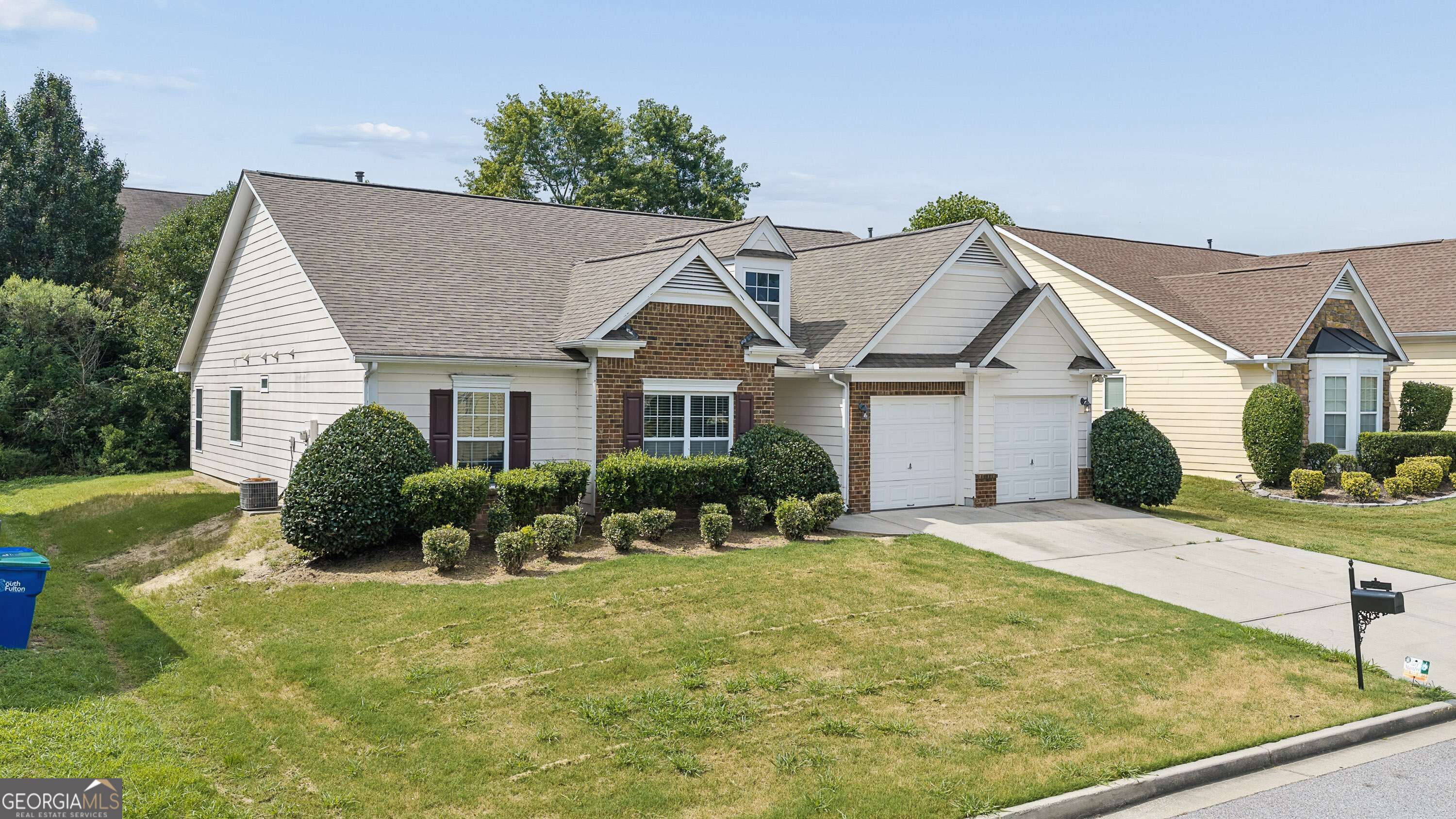 House exterior with multiple gables, brick accents, trimmed shrubs, and a two-car garage.