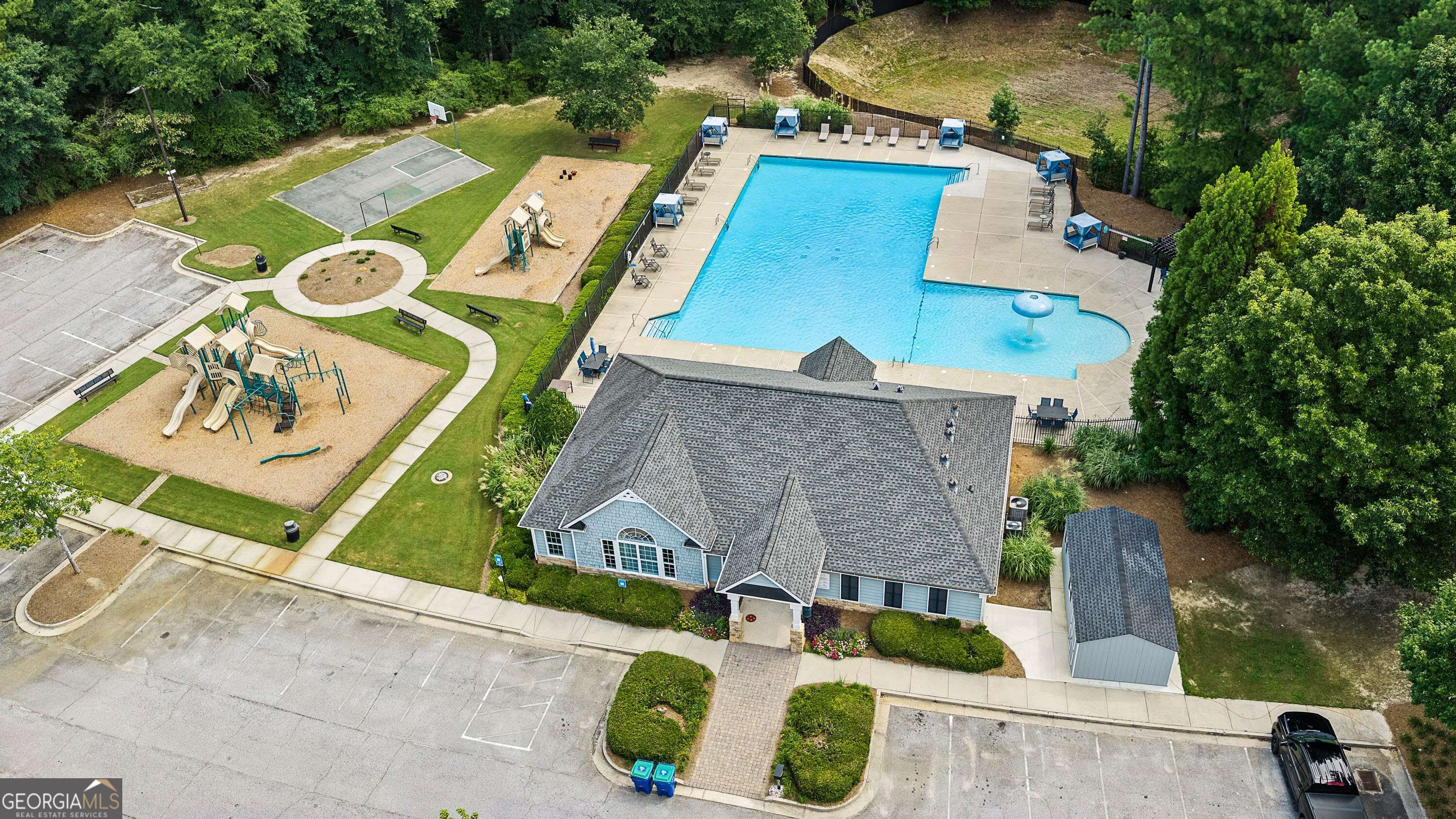 Aerial view of a community pool, clubhouse, playgrounds, and basketball court.