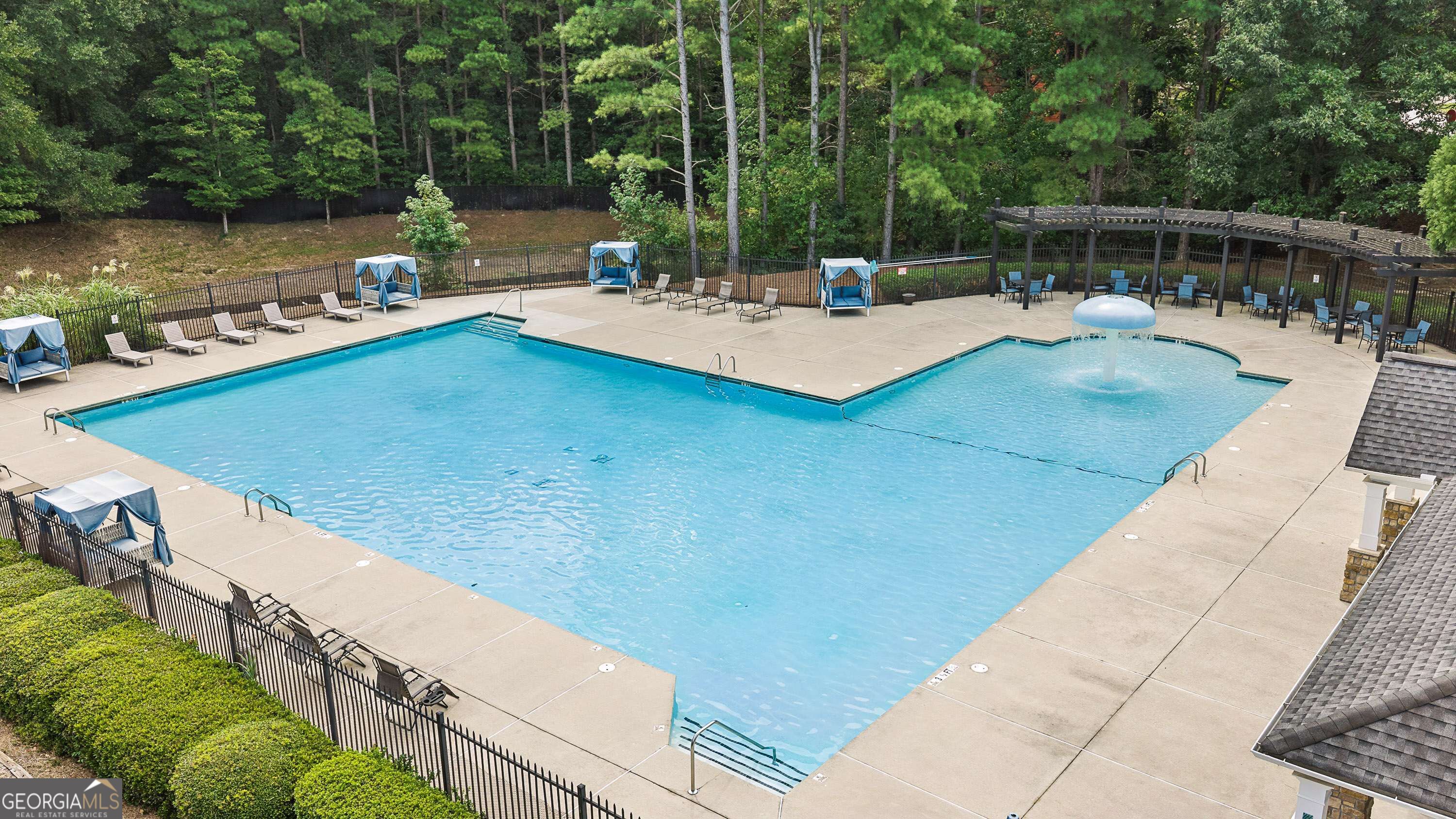 Community pool with a shallow wading area, bubbler fountain, blue cabanas, and pergola.