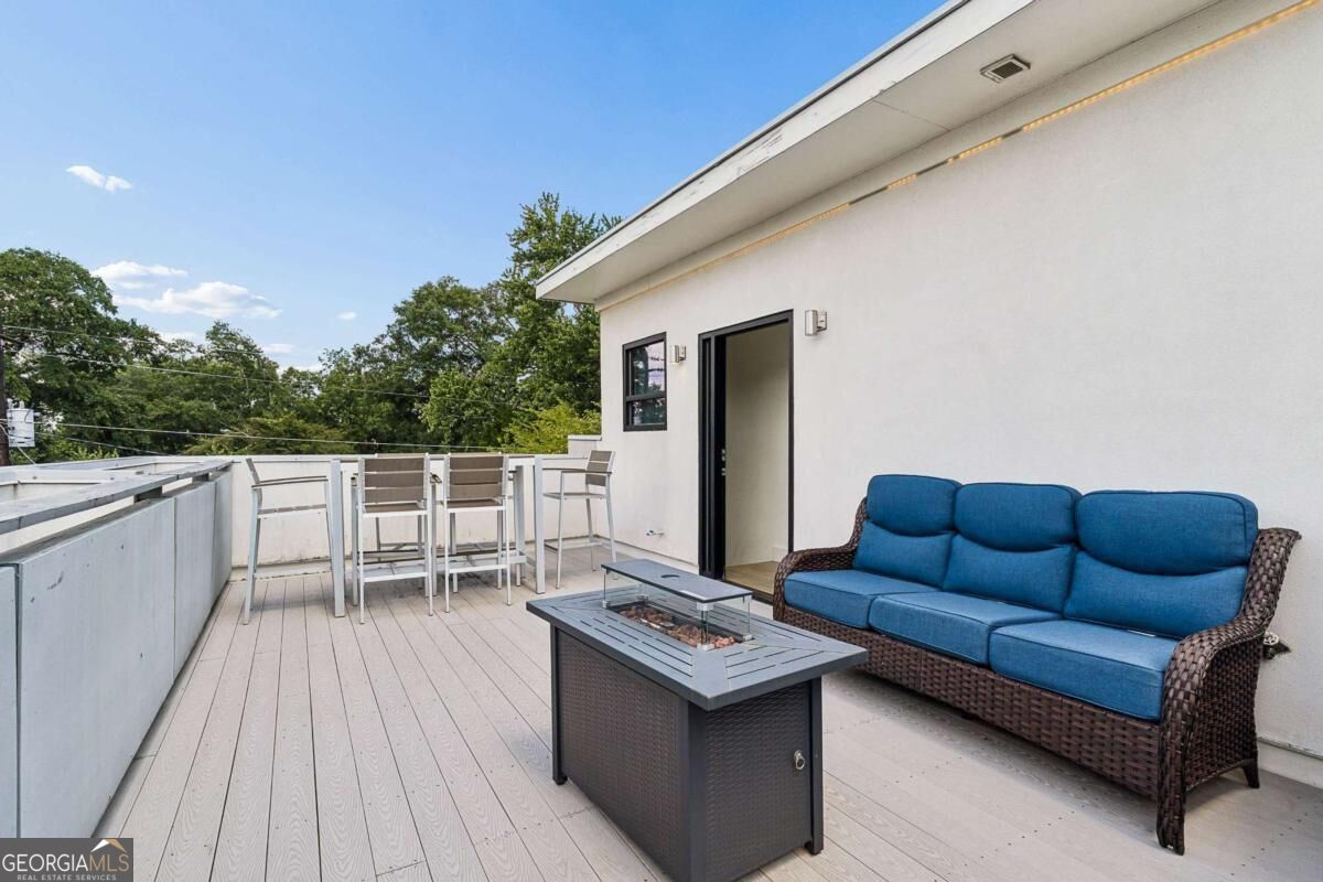 Rooftop deck with blue wicker sofa, glass fire table, and bar-height dining set.