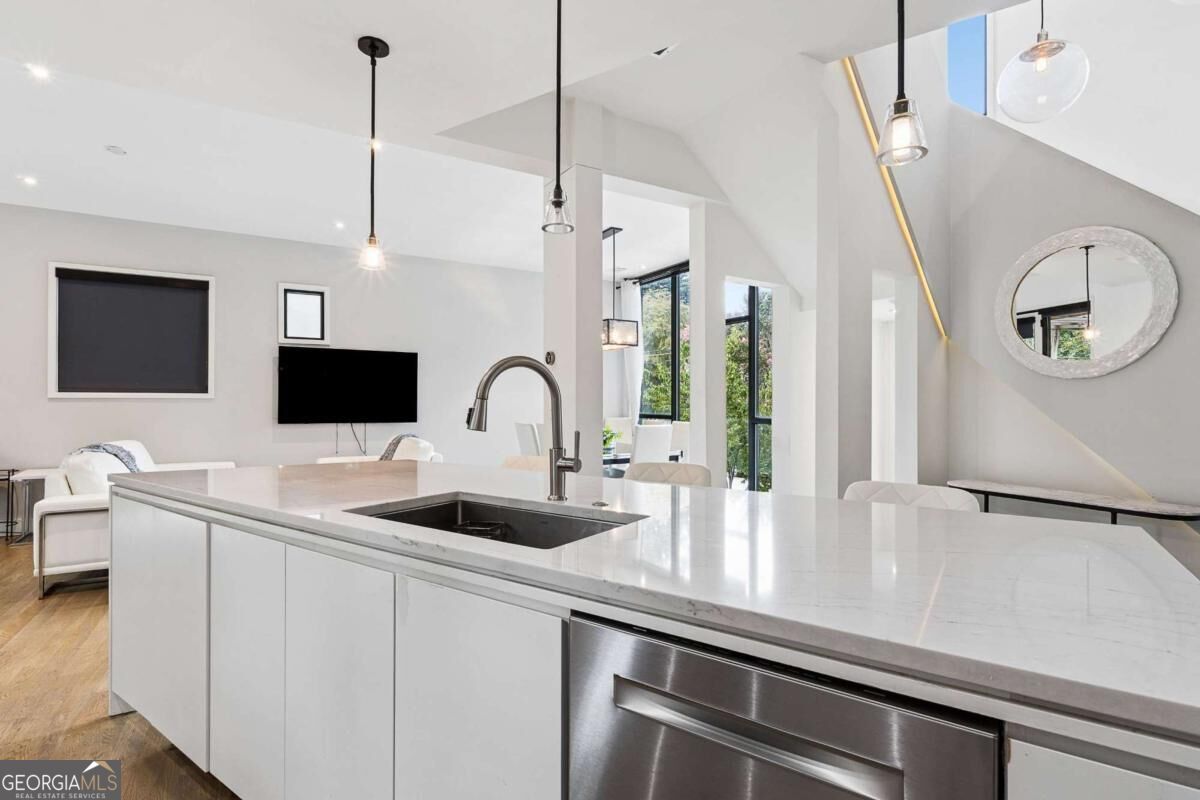 Open-plan kitchen with a large white island, undermount sink, and stainless-steel dishwasher.