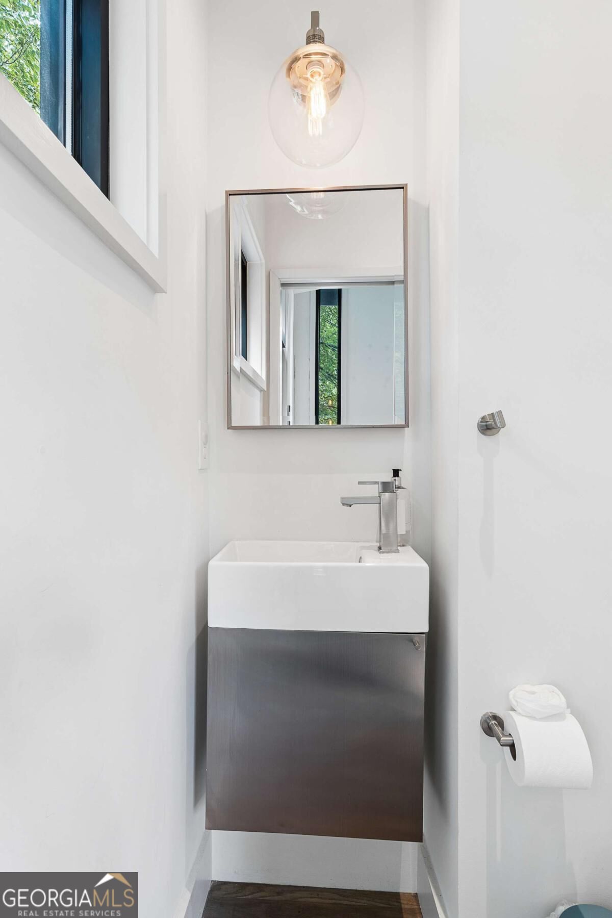 Modern bathroom with a floating vanity, rectangular sink, large mirror, and globe pendant light.