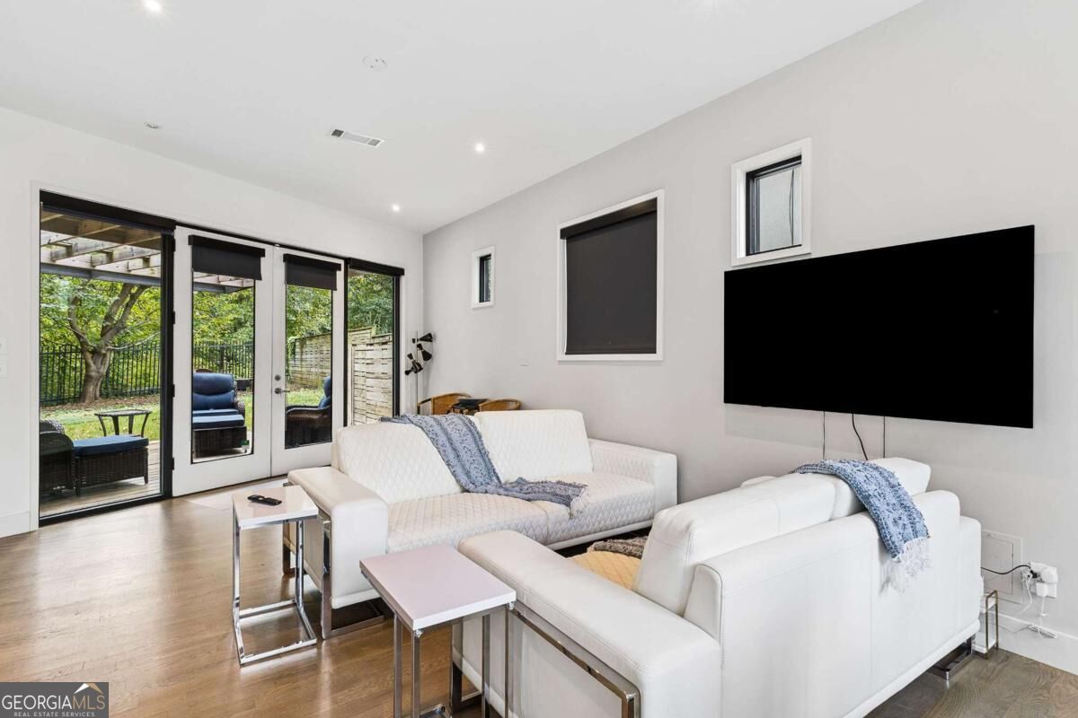 Living room with white sectional sofas and glass doors opening to a patio.