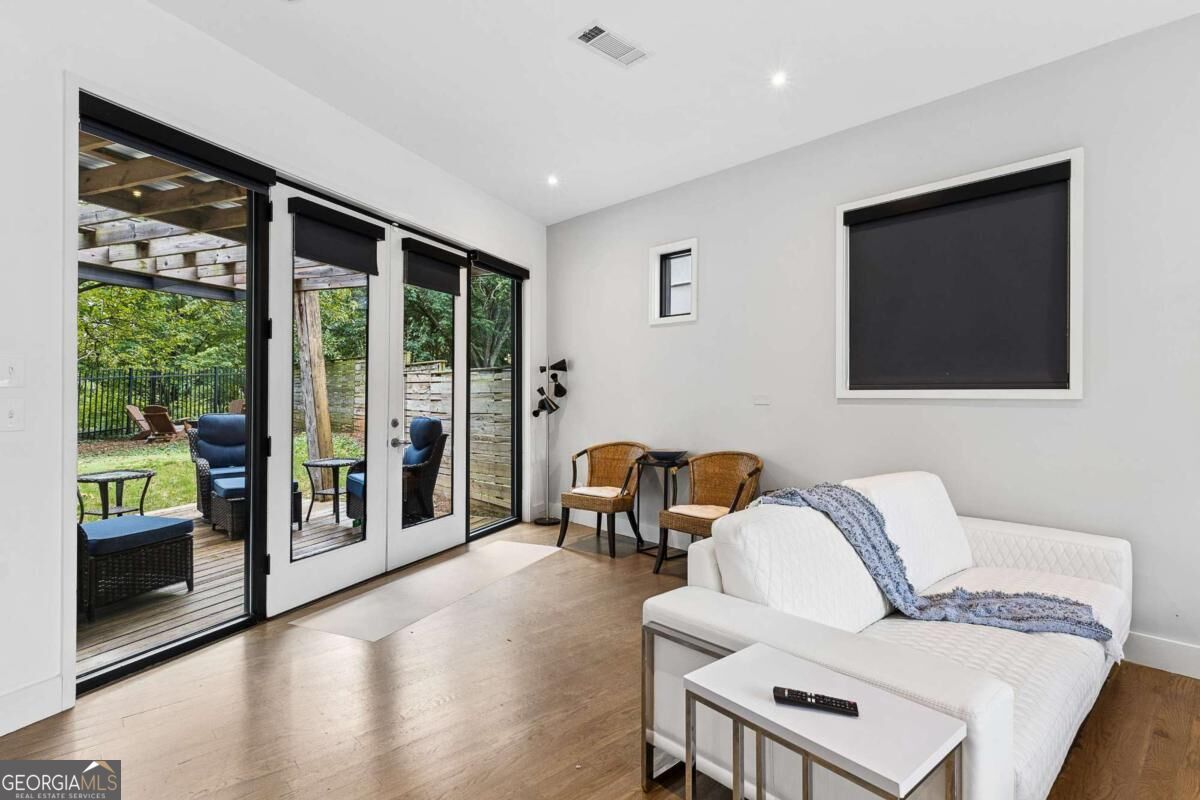Living room with a white sectional and wicker chairs beside glass doors opening to a deck.