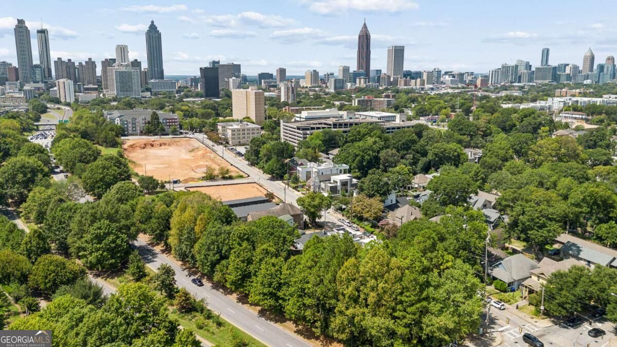 Aerial view of Atlanta’s skyline above a leafy neighborhood and cleared construction site.