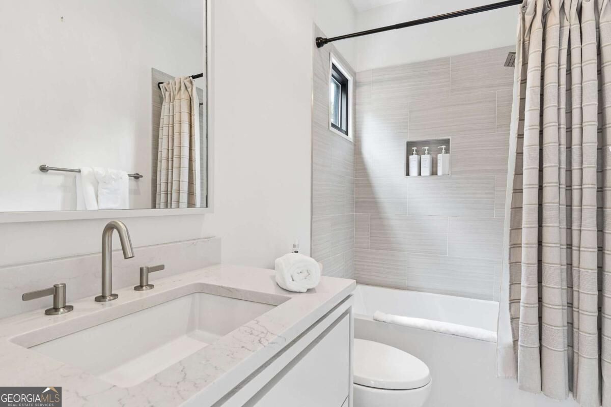 Bathroom with a marble-look vanity and tiled bathtub surround.