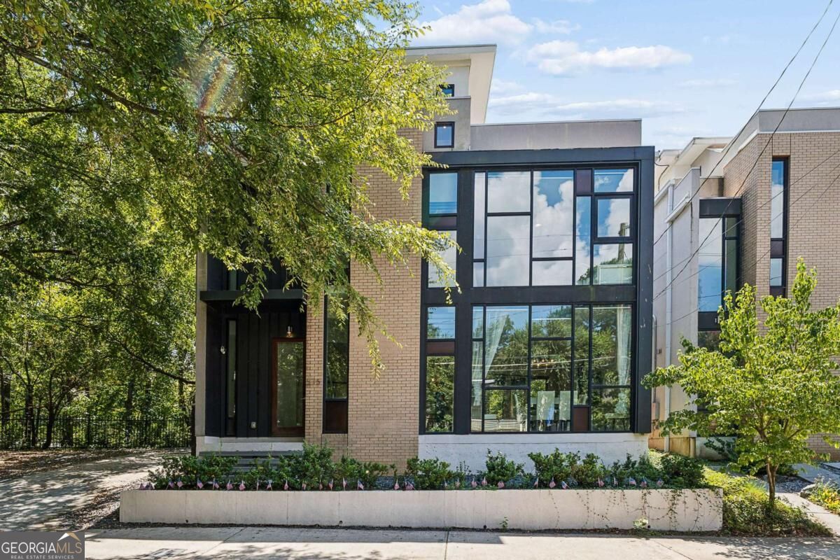 Contemporary brick home with large black-framed windows and a landscaped front entry.