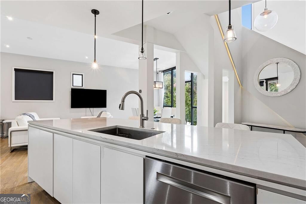 Modern kitchen with a large white quartz island, undermount sink, and stainless-steel dishwasher.