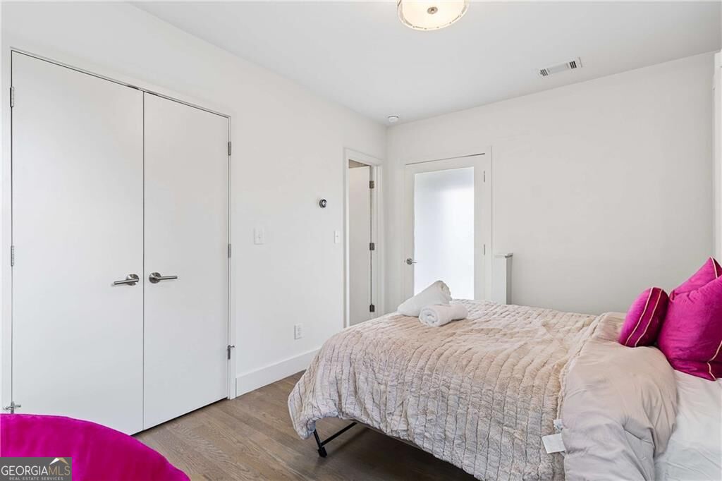 Bedroom with a quilted bed, magenta accent pillows, and double closet doors.
