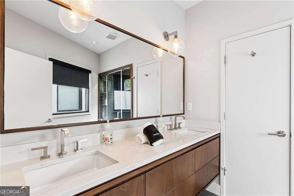 Bathroom with a double vanity, dark wood cabinets, globe lights, and a large mirror.