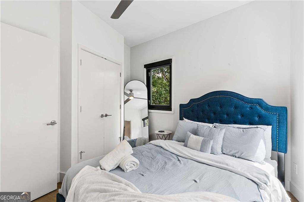 Bedroom with a blue tufted headboard, white bedding, and a black-trimmed window.