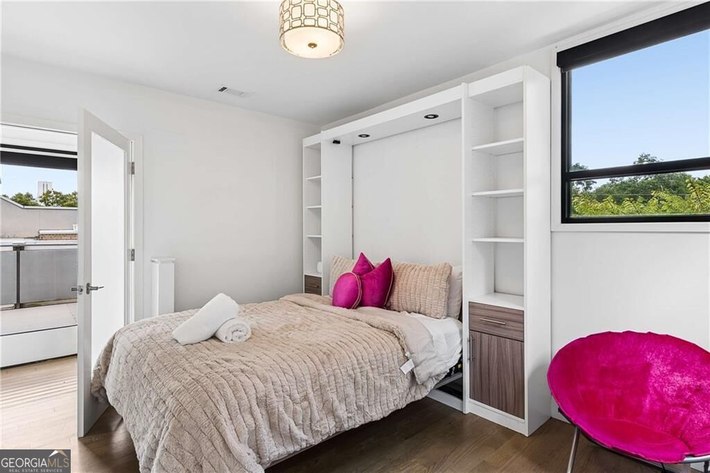 Bedroom with built-in shelving, magenta accents, and an open door to a balcony.
