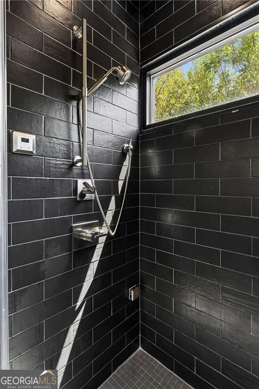 Black-tiled walk-in shower with chrome fixtures and a high horizontal window.