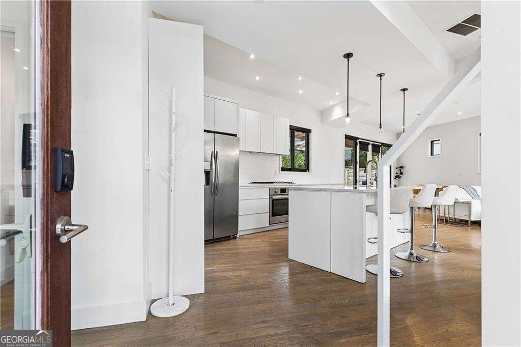 Open-plan kitchen with white cabinetry, stainless steel appliances, a large island, and adjoining dining area.