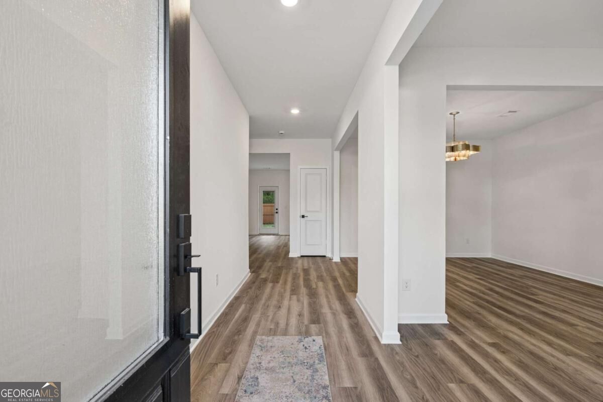 Home entryway with wood-look floors, glass front door, and open dining area.
