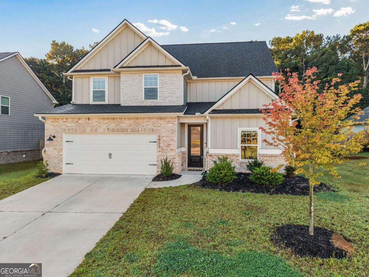 Two-story home with brick accents, a two-car garage, and autumn trees.