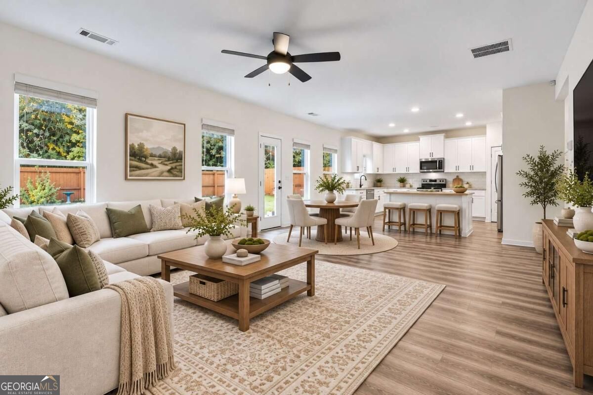 Open-concept living room and kitchen with a light sectional, wood coffee table, and white cabinetry.