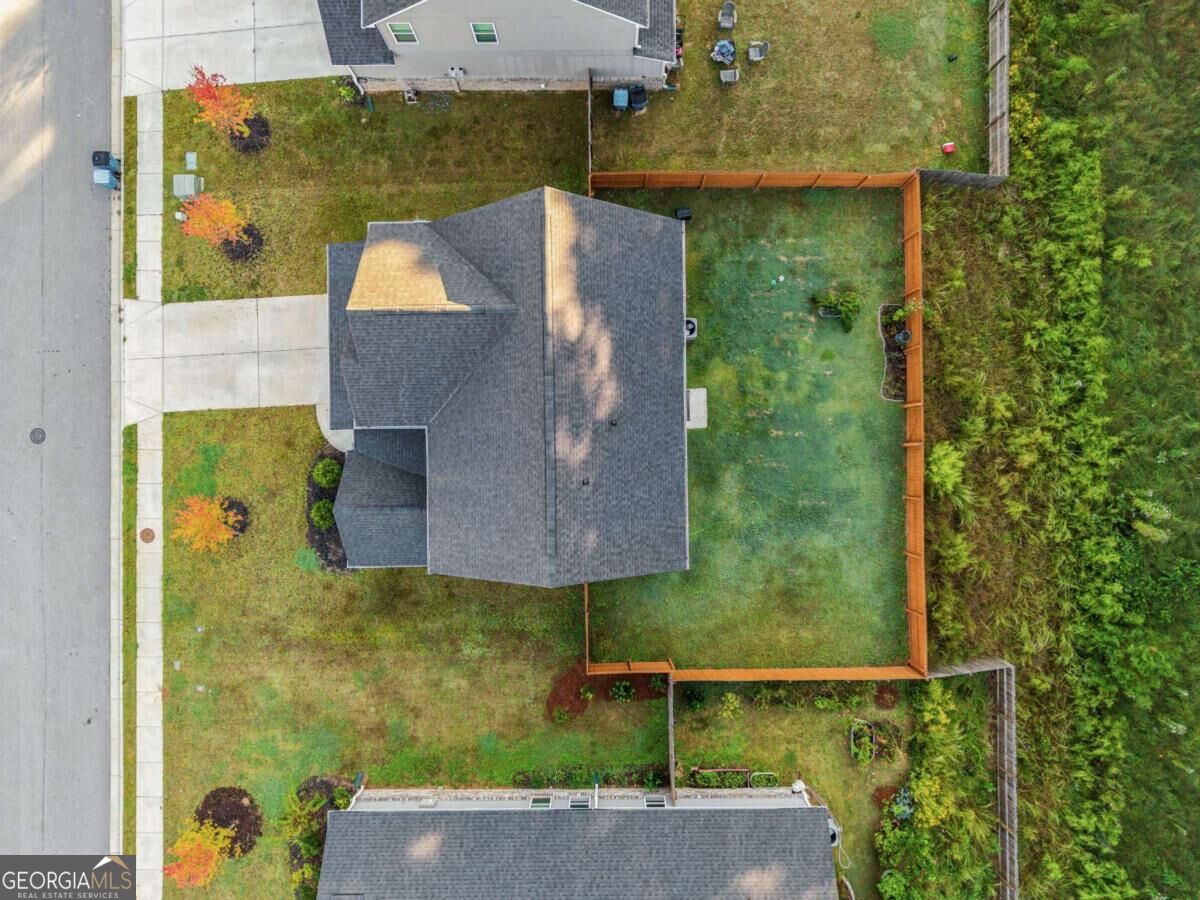 Aerial view of a house with a gray roof, lawn, and fenced backyard.