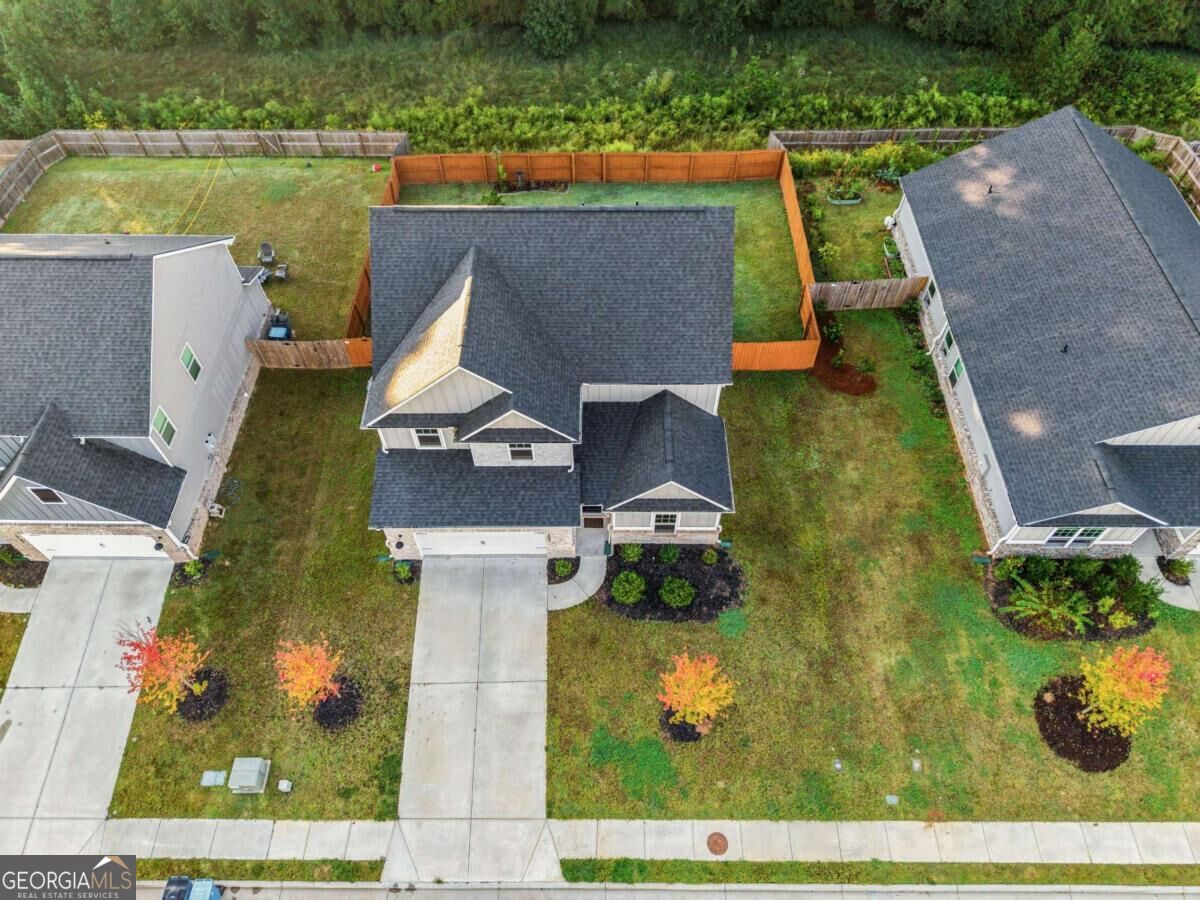 Aerial view of a two-story home with a fenced backyard and landscaped front lawn.