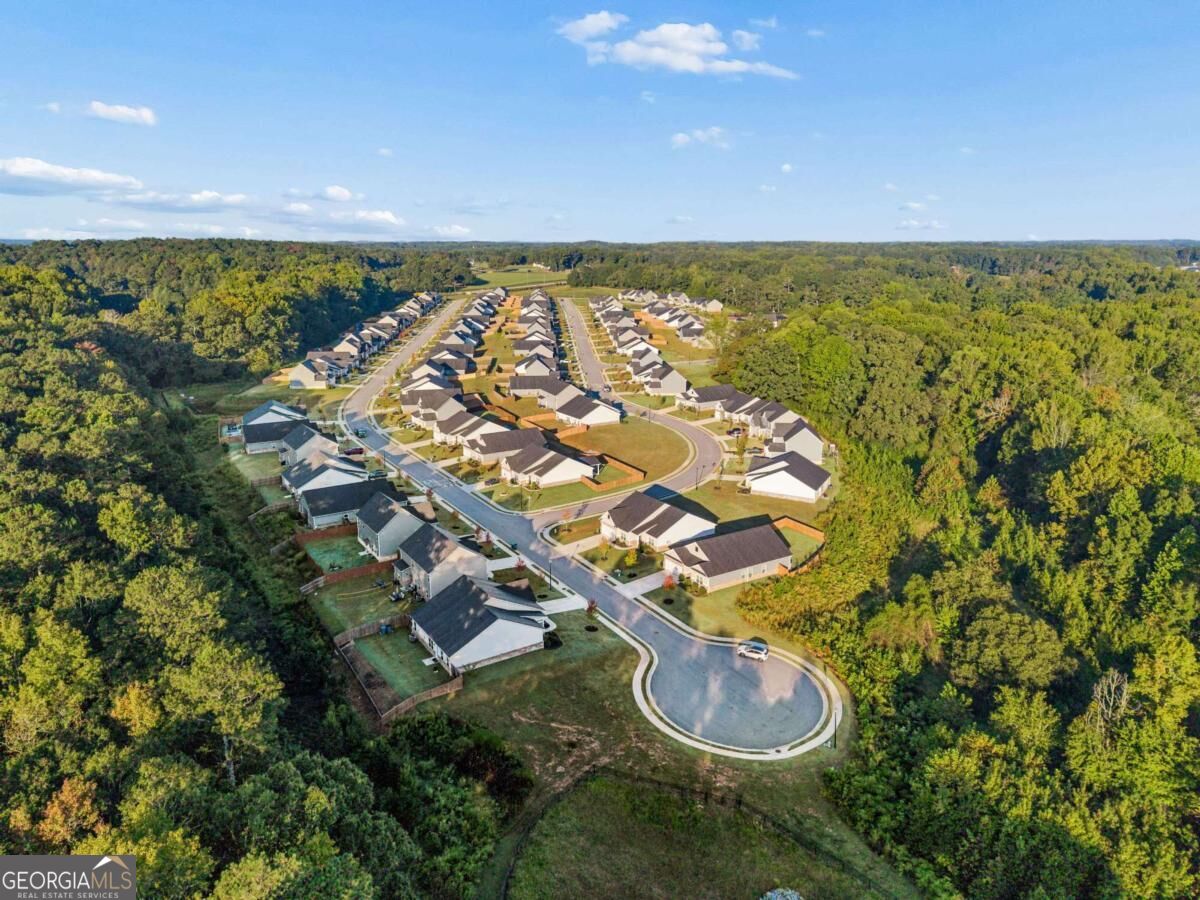 Aerial view of a subdivision with rows of homes, a cul-de-sac, and surrounding woods.