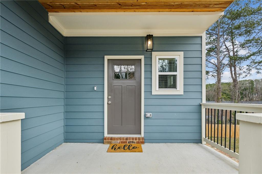 Covered front porch with blue siding, gray door, and a wood-plank ceiling.