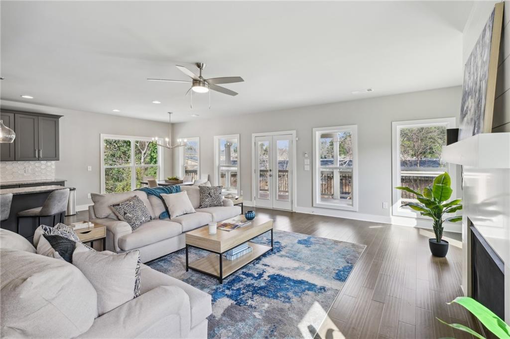 Open-plan living room with light sofas, blue patterned rug, and large windows overlooking a deck.