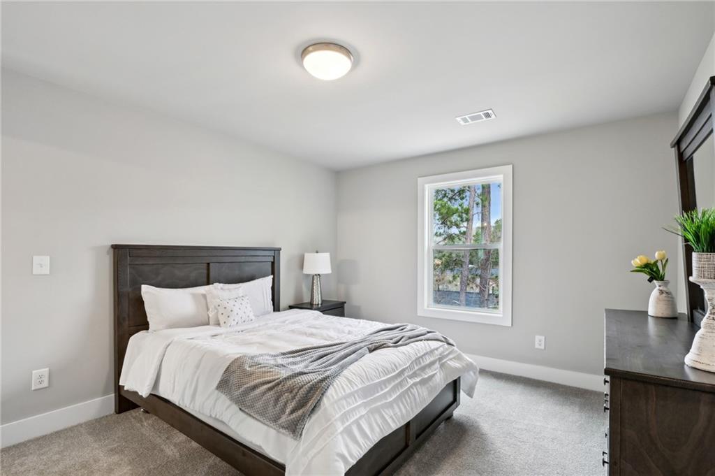 Staged bedroom with a dark wood bed, white bedding, gray throw, and a window overlooking trees.