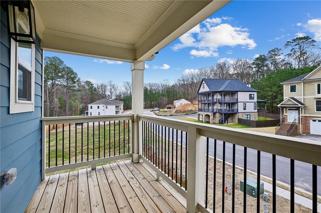 Covered wooden balcony with black railings overlooking neighboring homes and a residential street.