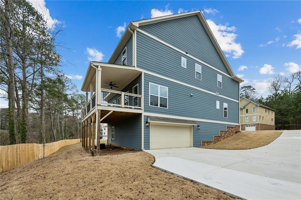Blue-gray two-story house with a raised covered deck and attached garage beside a sloping driveway.