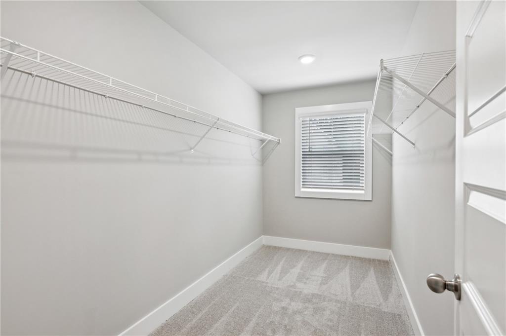 Walk-in closet with wire shelving on both walls and a window with blinds.