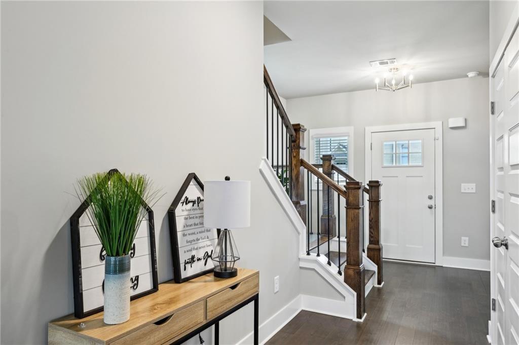 Entry foyer with a dark wood staircase, console table, and white front door.
