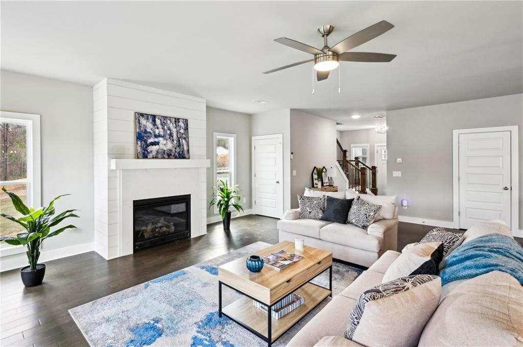 Staged living room with a white fireplace, light sofas, and a blue-and-white rug.