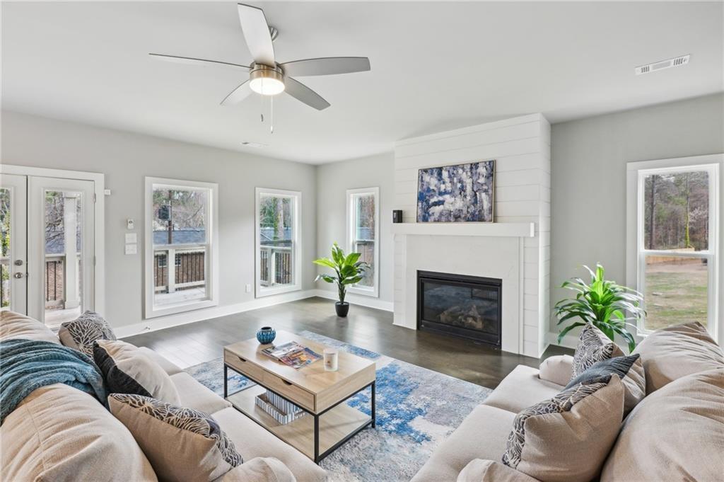 Staged living room with a white shiplap fireplace, large windows, and sofas around a coffee table.