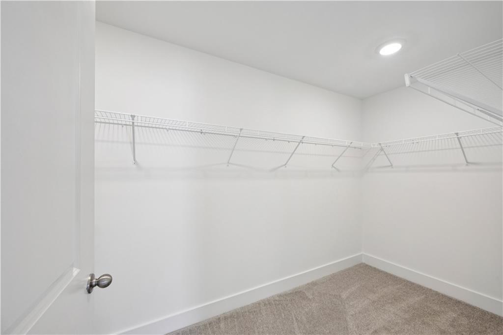 Empty walk-in closet with wraparound wire shelving and beige carpet.
