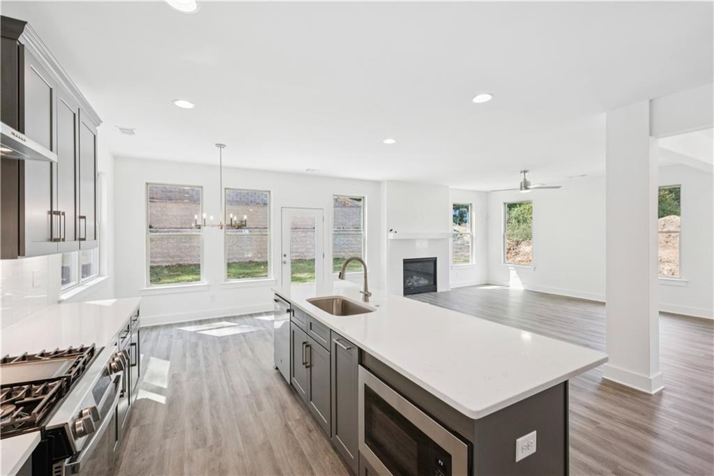 Open-plan kitchen with a large white island, gray cabinets, and an adjoining living area with a fireplace.