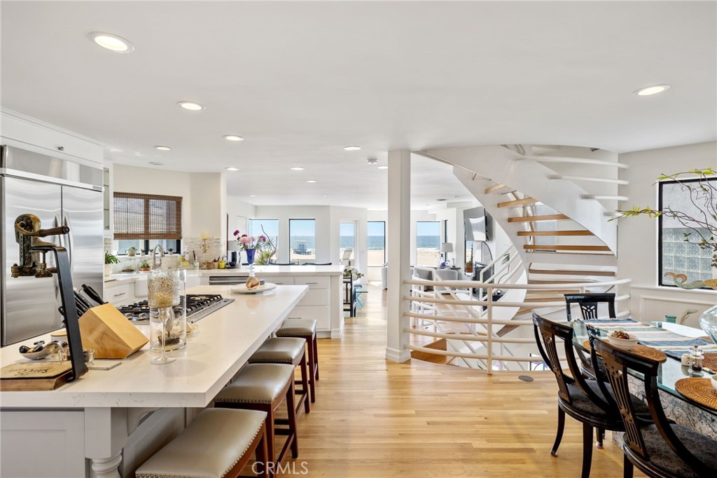 Open kitchen and dining area with a large island, curved staircase, and ocean views.