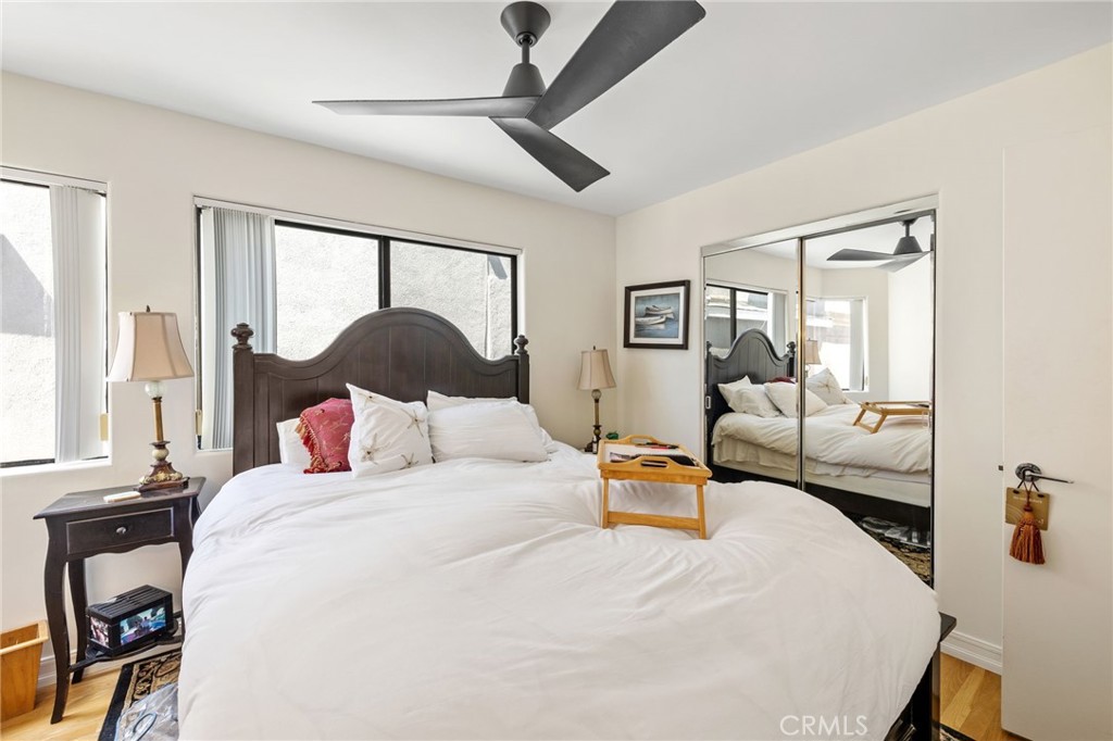 Furnished bedroom with a dark carved headboard, ceiling fan, and mirrored closet doors.