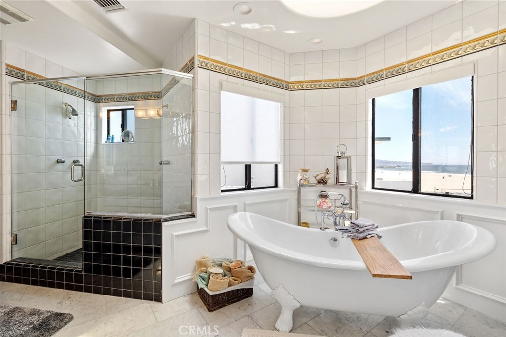 Bathroom with a freestanding tub and glass shower overlooking the ocean.